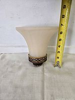 Flared glass shade of wall sconce with tape measure showing height