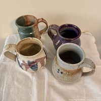 Top view of four stoneware mugs showing interior glazes and shapes