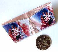 Obverse of coin beside folded pair of commemorative hockey stamps