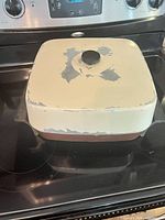 Closed skillet on stovetop showing cream lid with paint loss and copper base
