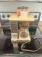 Full view of coffee maker with carafe, filter basket on top and filters