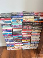 Front view of four tall stacks of mass-market paperbacks showing assorted titles and authors