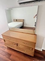 Front view of dresser with attached mirror, showing drawer arrangement and finish