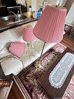 Floor lamp, table lamp, hanging chain lamp, pink shades visible on couch and rug