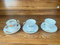 Front view of three teacup-and-saucer sets side by side