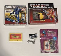 Front view of all items showing boxed Kre-O set, boxed Hot Rod figure, loose cassettes, weapons and sealed numeral candle