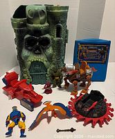 Group shot of all items including Castle Grayskull, vehicles, figures, book and accessory