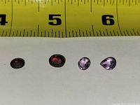 Four loose gemstones lined under ruler for scale