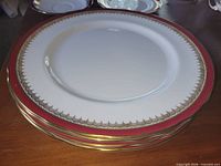 Stack of four Aynsley Ambassador Madone dinner plates showing burgundy and gold rim