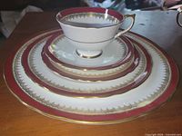 Stacked view of cup on nested plates showing pattern, gold trim and maroon band
