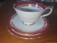 Cup stacked on saucer and plate showing maroon band and gold trim
