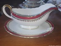 Side view of Aynsley gravy boat on underplate showing pattern and gilding