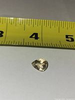 Pear-shaped citrine beside tape measure showing length near 10 mm