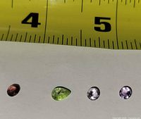 Four loose gemstones under ruler for scale