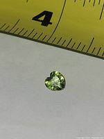 Top view of heart-cut peridot showing color and shape with ruler for scale