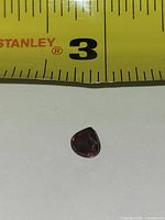 Pear-cut red garnet beside ruler showing size under 1⁄4 inch