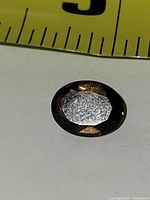 Top view of oval smoky topaz showing faceted crown against ruler for scale