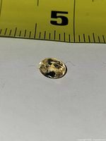 Top view of oval yellow gemstone next to ruler for scale