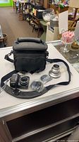 Group shot showing camera, silver lens adapter parts, adapter rings in packaging, and carrying case