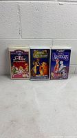 Front view of all three Disney VHS tapes standing side by side
