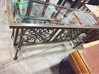 Full view of console table showing glass top and ornate iron frame