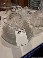 Group showing stacked etched plates, covered sugar bowl, ribbed tumblers and frosted globe
