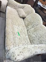 Full view of beige patterned sofa showing rolled arms and fabric wear