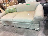 Front angled view of beige/cream 3-seat linen blend sofa with two green throw pillows