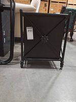 front view of black metal planter showing decorative flower medallion and feet
