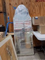 Mirror wrapped in plastic leaning against wall showing arched top and mirrored frame
