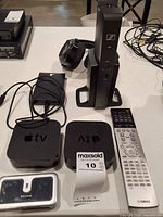 Top view showing Sennheiser base with headphones, two Apple TV units, Yamaha remote, Belkin reader, cables