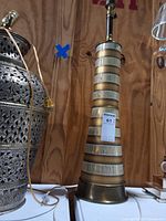 Full view of tapered brass and glass table lamp with cord and finial