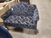 Front and side view of loveseat showing upholstery pattern and wooden cabriole legs