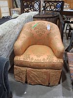Front view of peach/coral gold damask barrel armchair showing upholstery, removable cushion and skirt