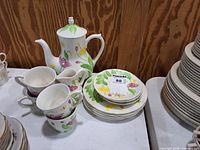 Teapot, stacked cups, creamer, and floral saucers on table