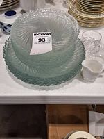 Stack of seafoam swirl pressed glass plates with MaxSold tag visible