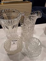 All four clear glass pieces grouped: flared vase, handled pitcher, low diamond bowl, spherical rose bowl