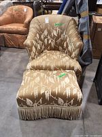 Front view of slipper chair and ottoman showing upholstery and fringe