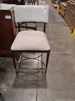 Front view of stool showing upholstery color, metal frame, and brass accents