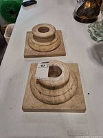 Two travertine collar-base pieces showing stone texture and mounting hole
