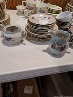 Stack of floral dessert plates with creamer and sugar bowl
