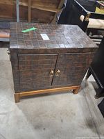 Front view of cabinet showing tiled exterior and brass pulls