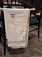 Folded white flat sheet on hanger showing fabric and hem detail