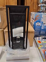 Lantern partially unwrapped showing black metal frame, clear glass, bulb socket