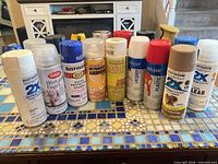 Front view of all spray paint cans displayed on tiled surface