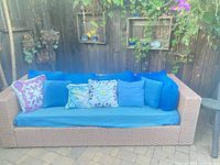 Front view of wicker sofa with blue cushions and patterned pillows