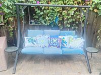 Front view of porch swing with cushions, pillows, side trays visible