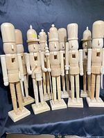 Group of nine unfinished wooden nutcrackers on bases