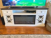 Front view of console showing fireplace insert, drawers, open shelf, glass door cabinets