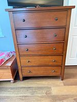 Front view of five-drawer dresser with metal knobs